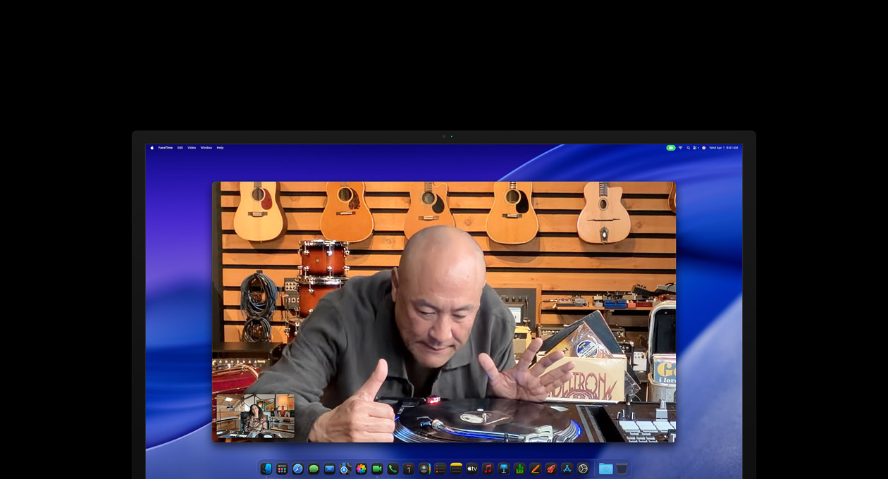 En person i en musikaffär tittar på en skivspelare i ett videosamtal. Han syns mitt i bilden tack vare Center Stage-kameran.