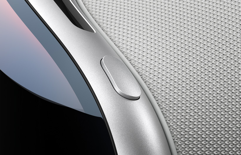 Die Nahaufnahme zeigt die geschwungene obere linke Ecke der Apple Vision Pro, die obere Taste hat das gleiche Aluminiumgehäuse wie der Rahmen der Apple Vision Pro, das geschwungene Glas der Vorderseite und ein Teil der oberen Lüftungsöffnung sind ebenfalls zu sehen